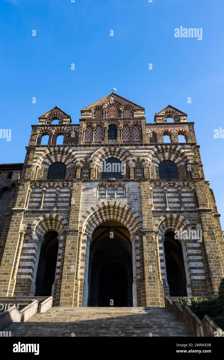 Façade romane polychrome de la Cathédrale Notre-Dame du Puy illuminée par un soleil d’hiver depuis la Rue des Tables au Puy-en-Velay, en Auvergne Stock Photo