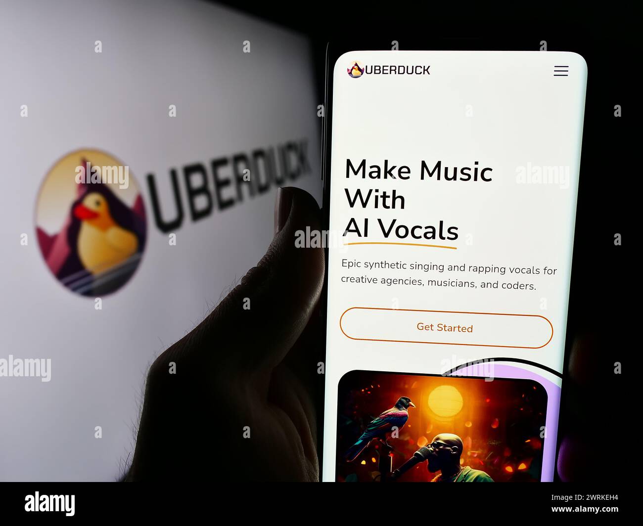 Person holding cellphone with webpage of US artificial intelligence music company Uberduck Inc. with logo. Focus on center of phone display. Stock Photo