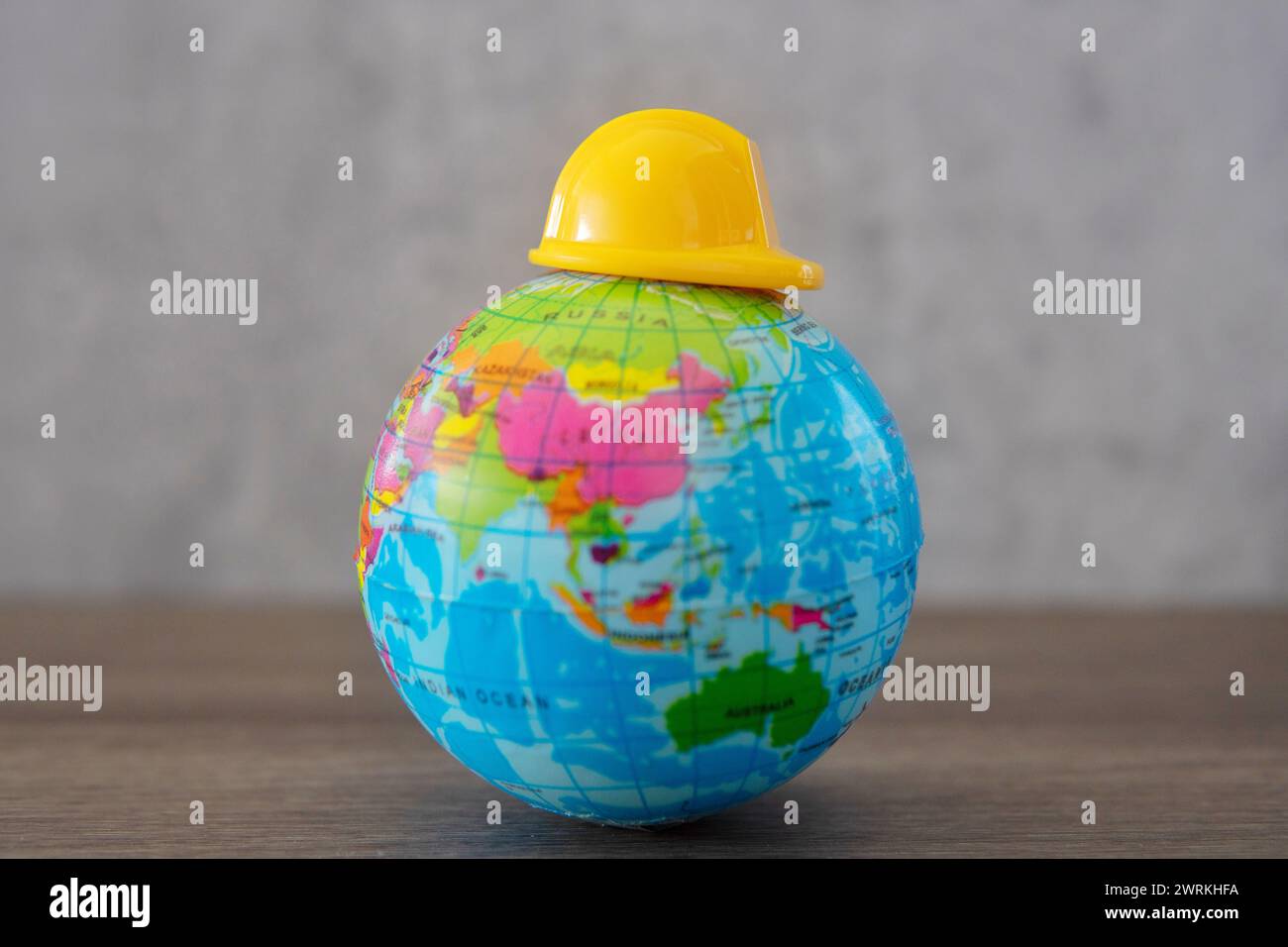 Hard hat on top of world globe. Copy space for text. Labor day, safety first concept. Stock Photo