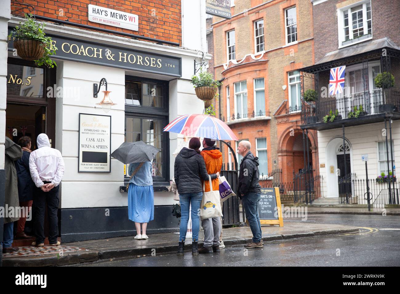 People watch the coronation of King Charles III on screen at a pub in central London. Stock Photo