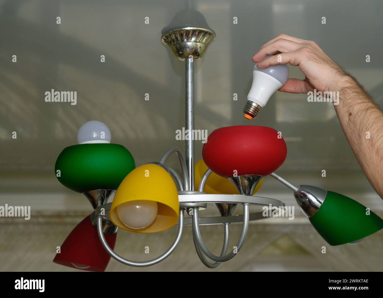 replacing the light bulb in the chandelier. LED lamp. Stock Photo