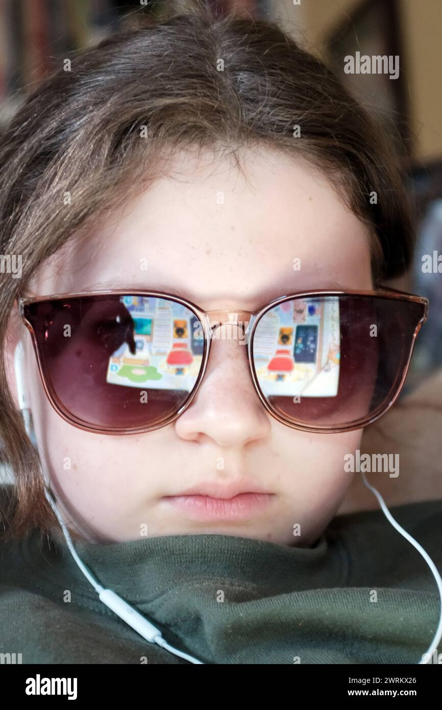 Screentime - youngster on device with internet pages reflected in glasses. Stock Photo