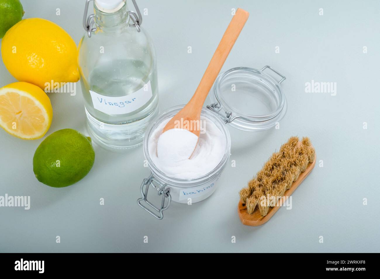 Natural household cleaning products baking soda, white vinegar, citrus fruit, brush on a gray background. Eco-conscious and environmentally friendly Stock Photo