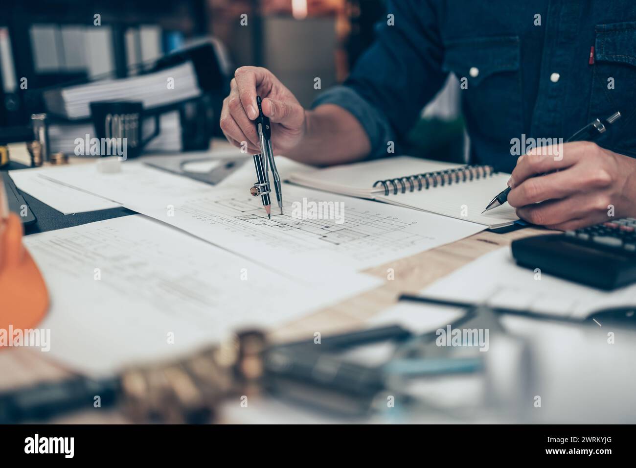 Architect using divider compass working on blueprint and make a note on book. Construction concept. Engineering tools Stock Photo