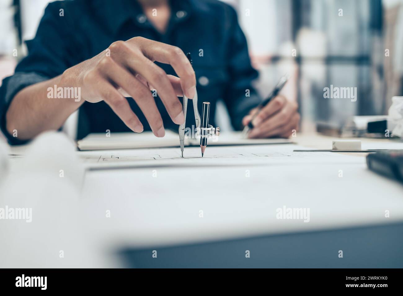 Architect using divider compass working on blueprint and make a note on book. Construction concept. Engineering tools Stock Photo