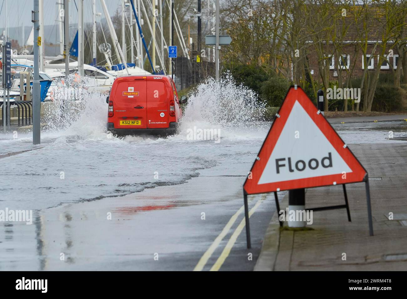 Weymouth, Dorset, UK.  13th March 2024. UK Weather:  A van drives through floodwater from a high spring tide on Commercial Road next to the harbour at Weymouth in Dorset on a warm overcast morning.  Picture Credit: Graham Hunt/Alamy Live News Stock Photo