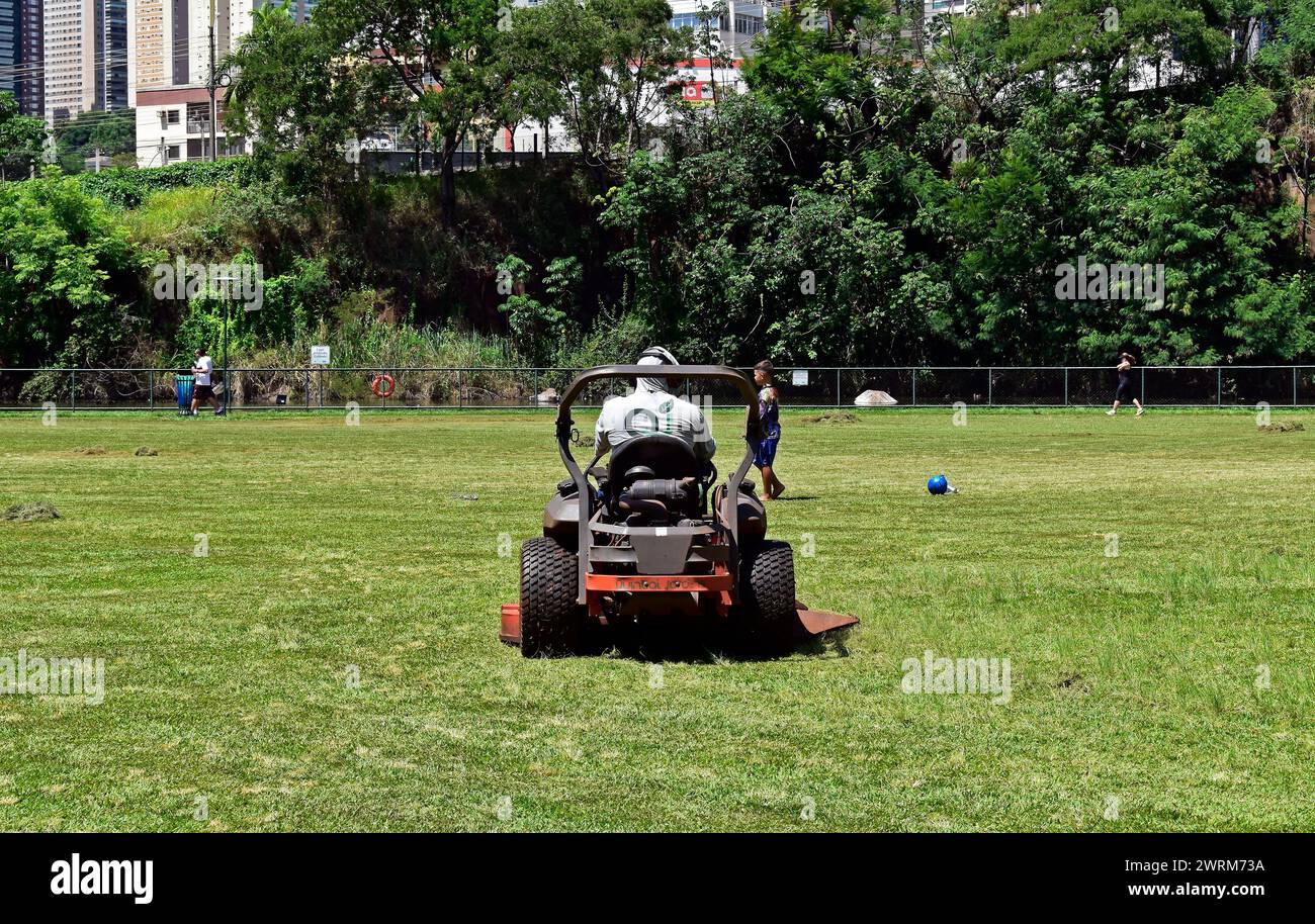 RIBEIRAO PRETO, SAO PAULO, BRAZIL - December 26, 2023: Man mowing the lawn in public park Stock Photo