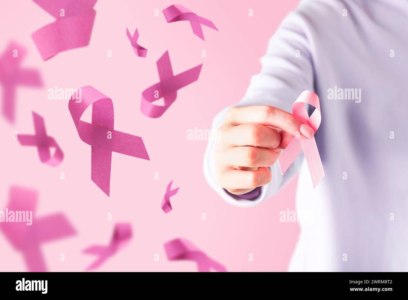 Pink Breast Cancer Awareness Ribbon. Female hand holding pink ribbon flying symbol of fight against breast cancer. Breast cancer awareness and October Stock Photo
