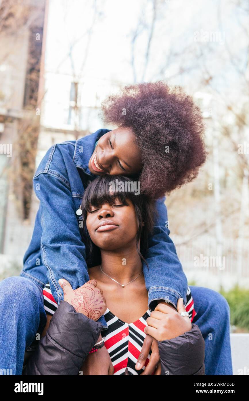 In a candid moment, one sister leans on another, sharing laughter and companionship, highlighting the warmth of familial bonds Stock Photo
