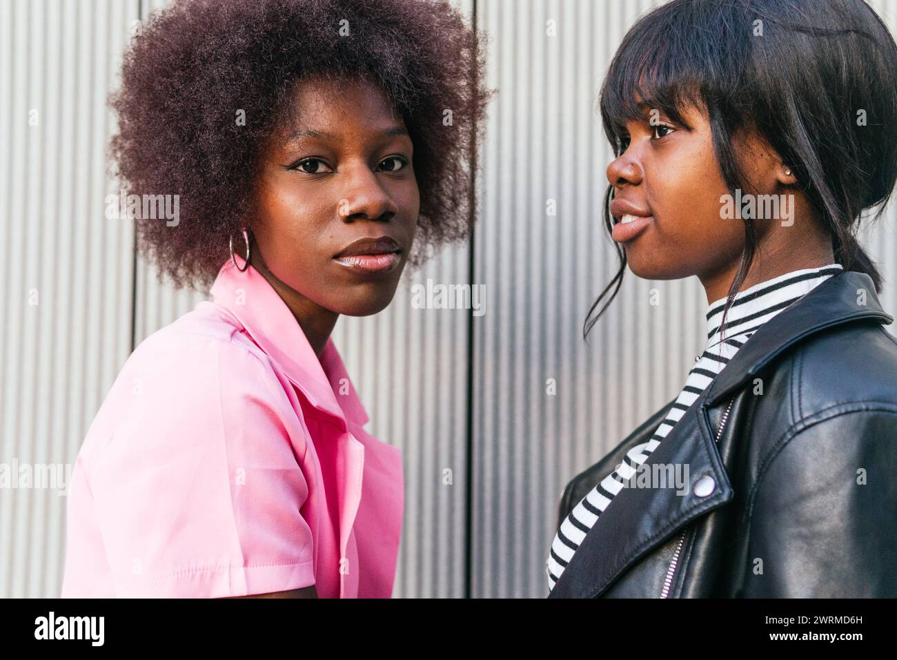 A side-by-side portrait of two black sisters, each with her own unique style, showcasing a blend of softness and edginess Stock Photo