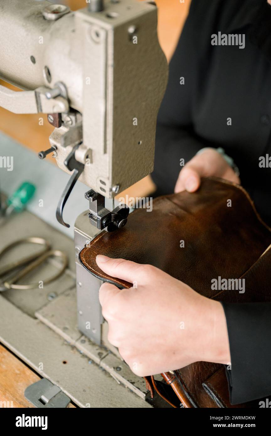 Close-up of anonymous shoemaker's hands crafting a leather shoe using sewing machine in an Austrian workshop. Stock Photo