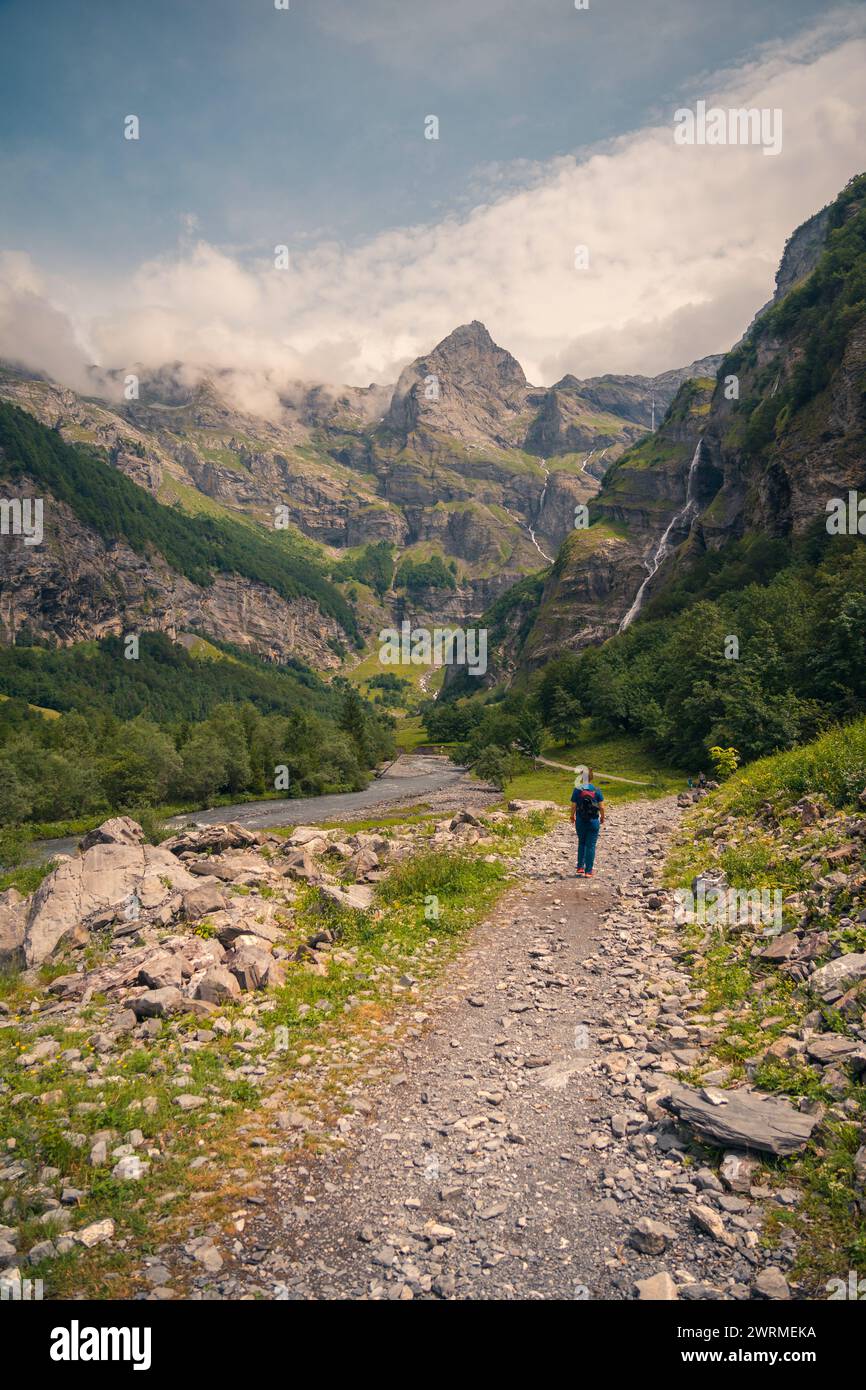 back view of an unrecognizable lone hiker walking on a rocky trail in ...