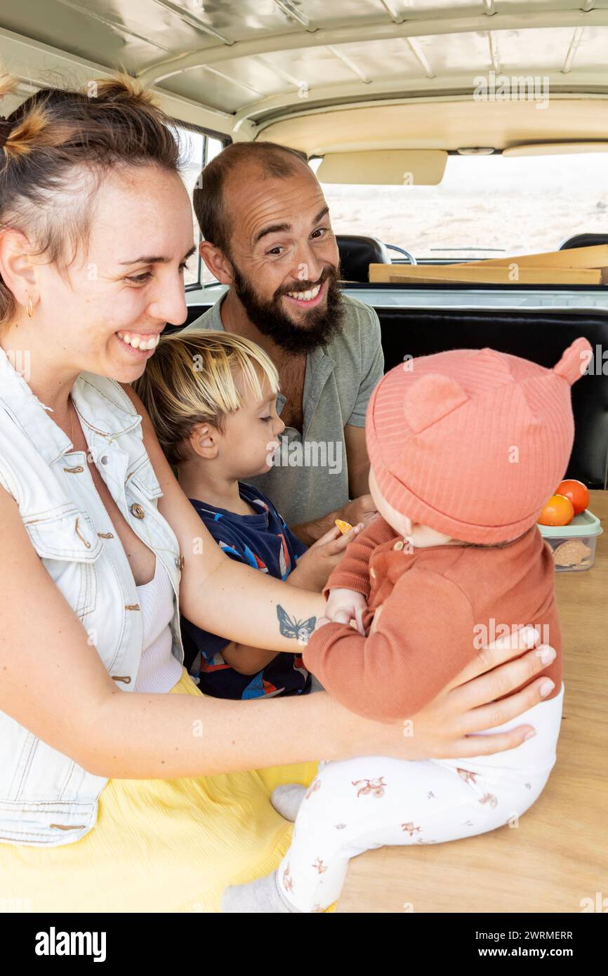 A happy family shares a joyful moment together inside a vintage van, radiating a carefree and loving atmosphere. Stock Photo