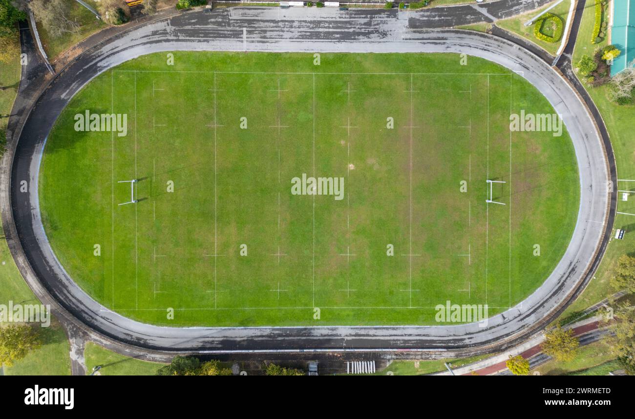 Aerial shot from a drone capturing an empty, well-maintained rugby field with visible pitch markings, surrounded by a curved running track, showcasing Stock Photo