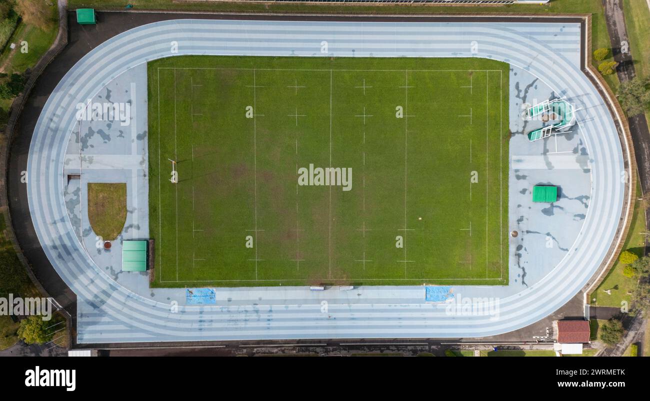 Drone shot capturing the top-down view of a sports complex featuring a track, a field, and surrounding facilities. Stock Photo