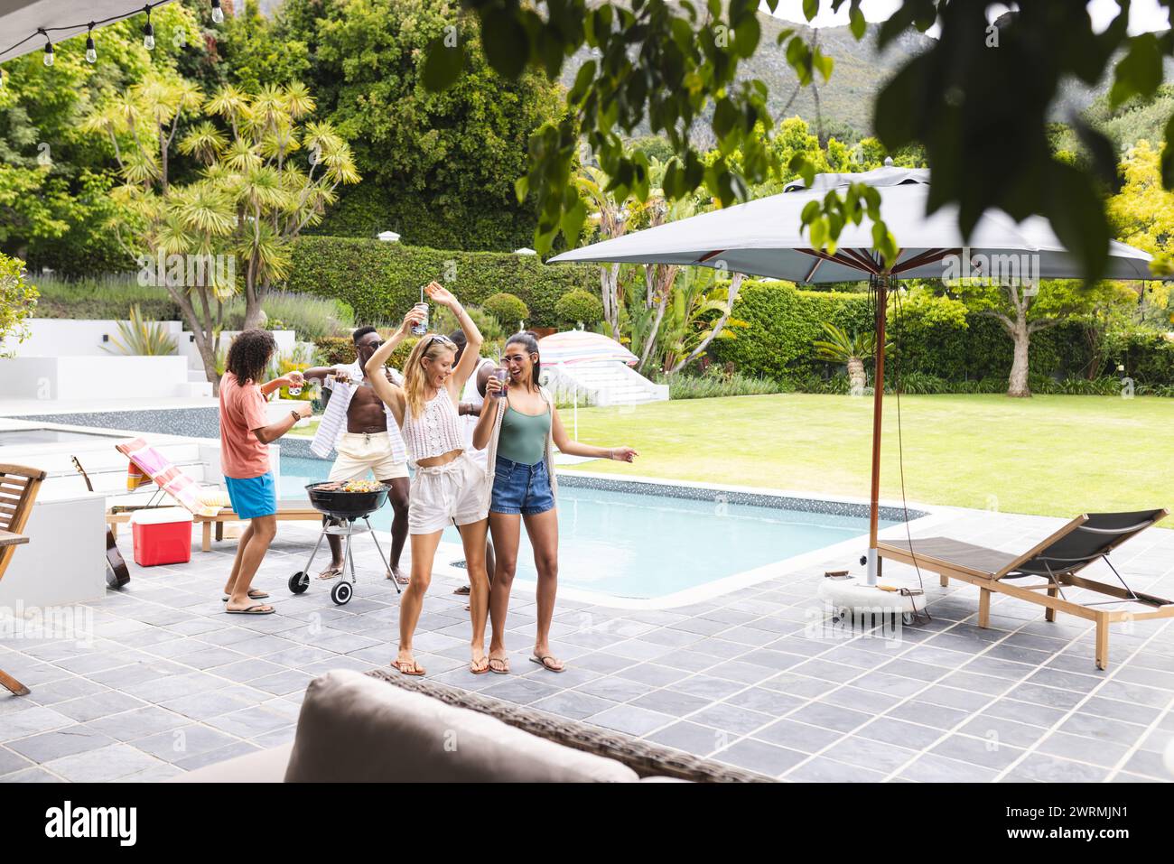 Diverse group of friends enjoying a barbecue by the poolside with copy space Stock Photo