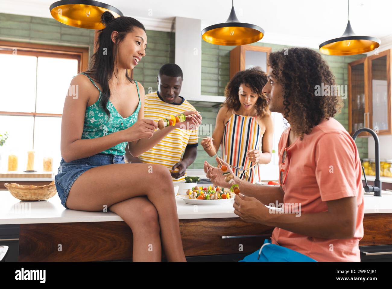 Diverse group of friends preparing food in a modern kitchen Stock Photo