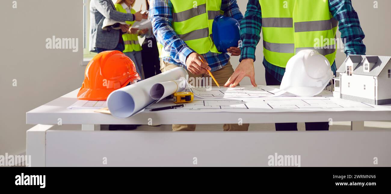 Professional builders discussing architect project at construction site Stock Photo