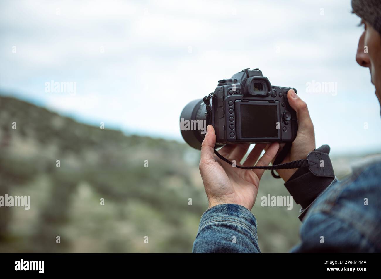 Details on the digital camera in the hands of male photographer capturing the beauty of nature, photographing mountains. Travel photographer taking pi Stock Photo