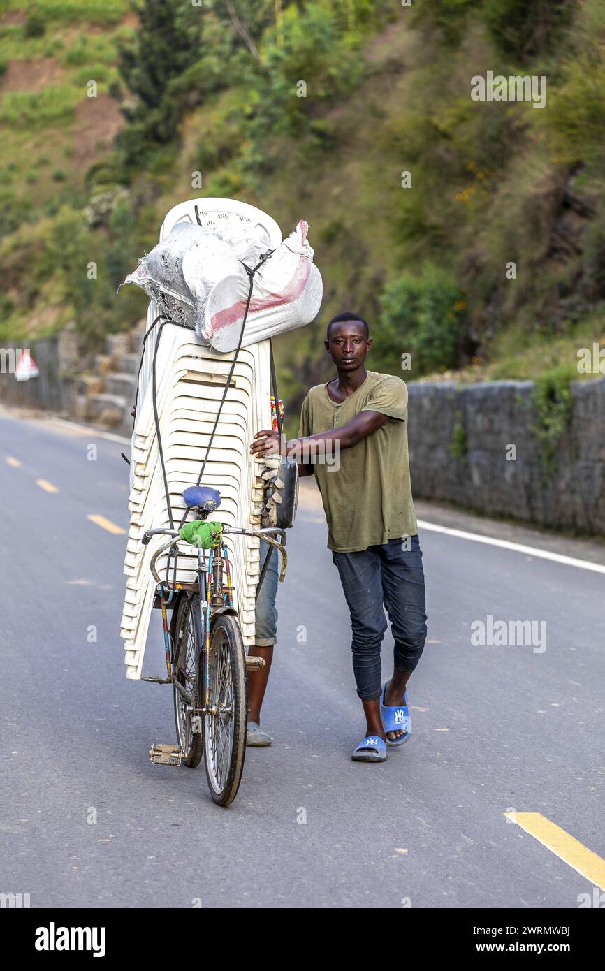 Man pushing a load of plastic chairs on a bike in western Rwanda, Africa Copyright: Godong 809-8945 Editorial Use Only Stock Photo