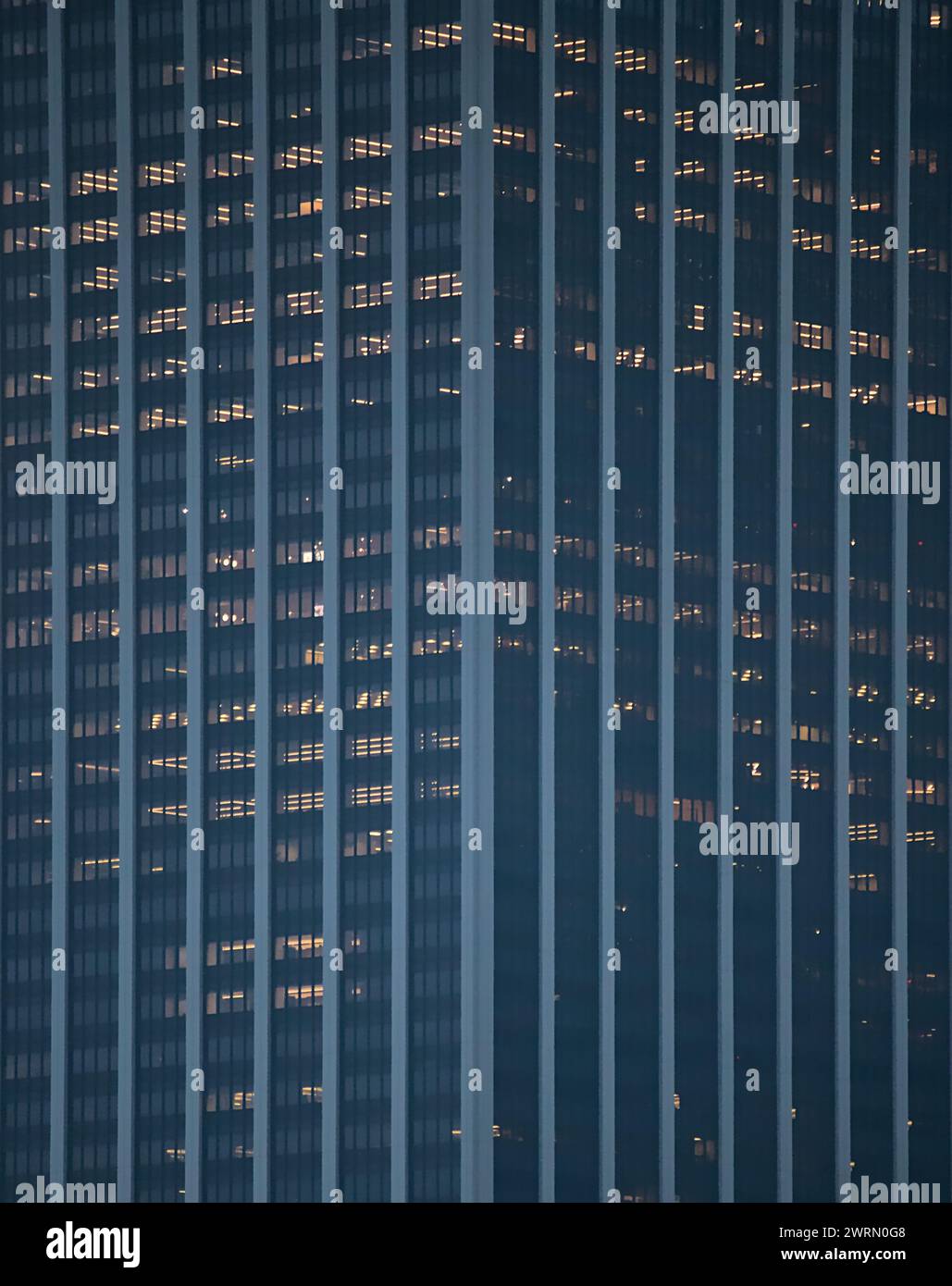 tall office building detail (straight lines, symmetry) dark with lights on in some windows (skyscraper, downtown urban tower) nyc, manhattan, new york Stock Photo