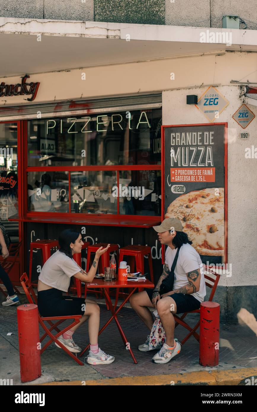 people sit at tables in front of a pizzeria in Buenos Aires, Argentina - mar 2th 2024. High quality photo Stock Photo