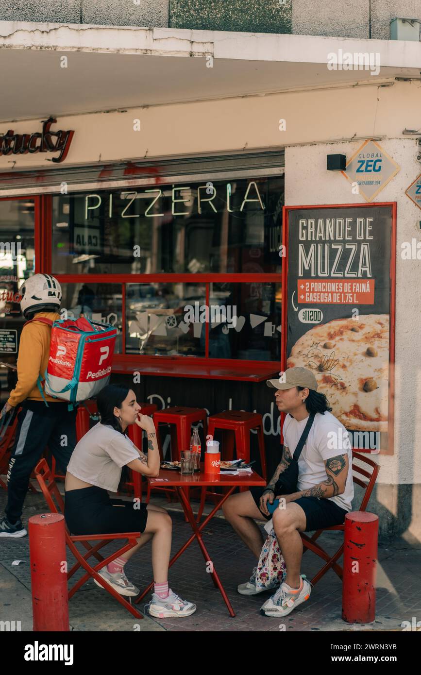 people sit at tables in front of a pizzeria in Buenos Aires, Argentina - mar 2th 2024. High quality photo Stock Photo