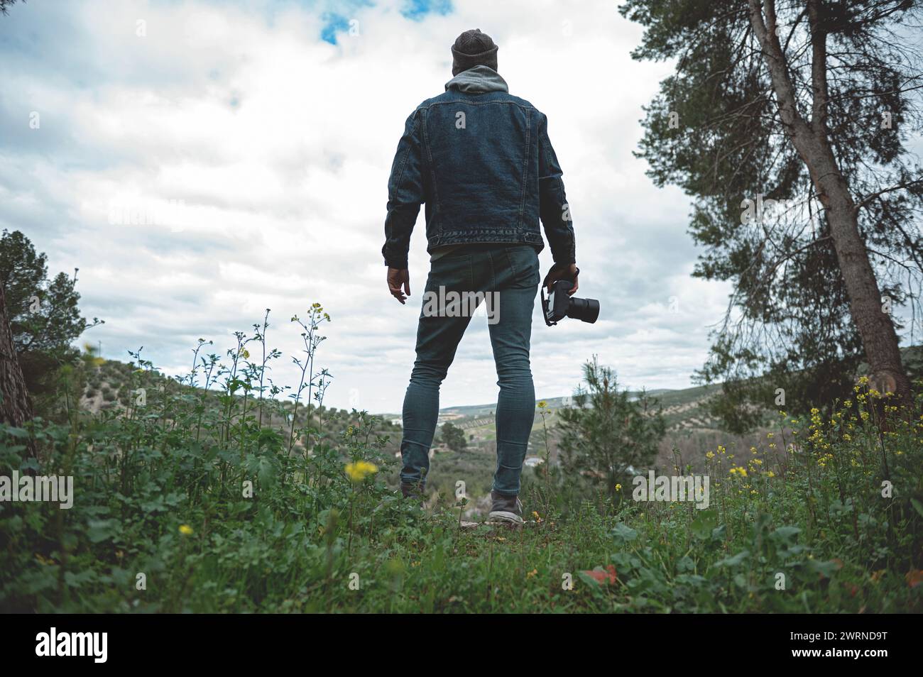 Full length portrait of a hiker man, a traveler photographer holding professional digital camera, admiring the mountains while trekking in the early s Stock Photo