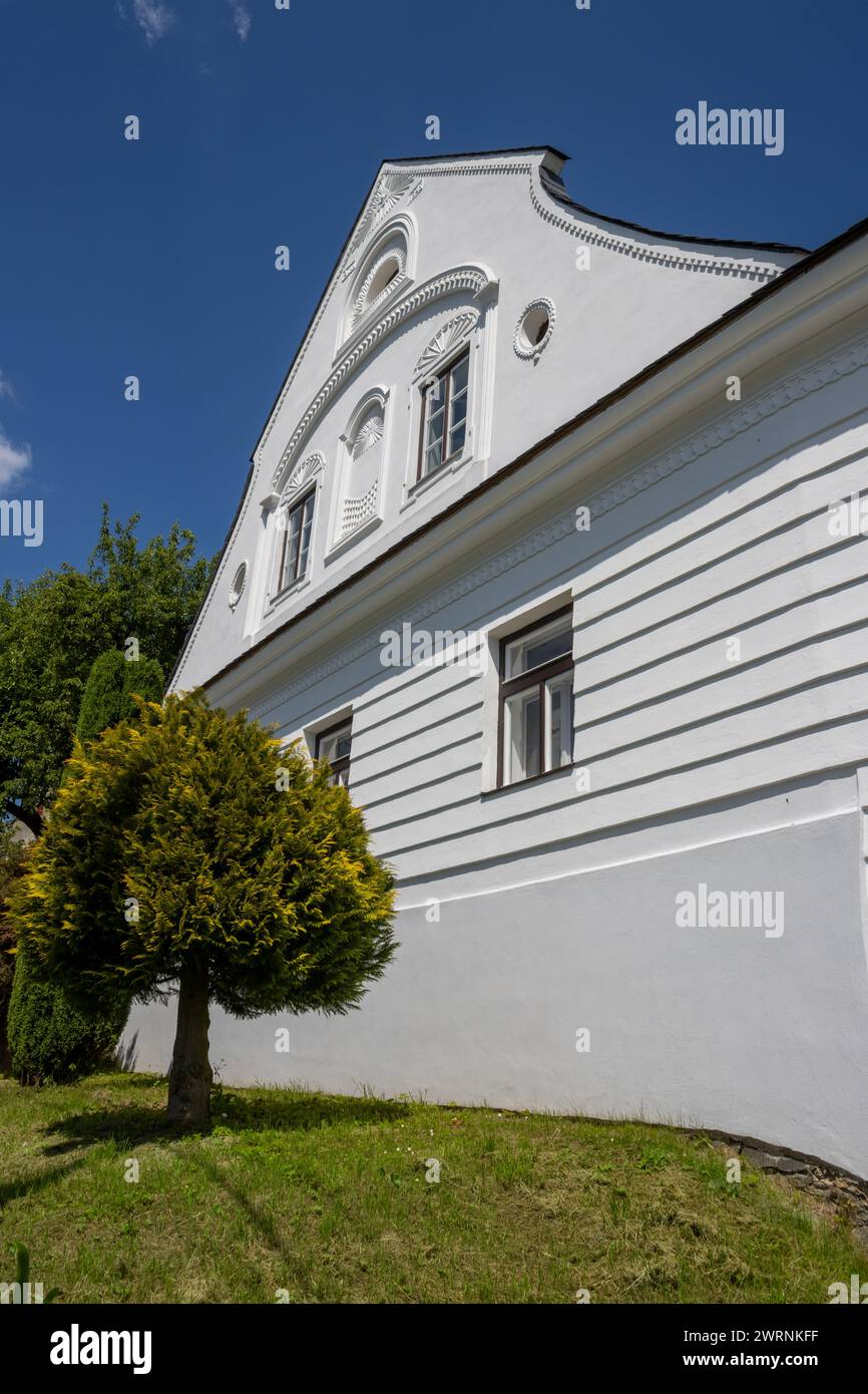 Perfect example of a sensitive renovation of an old house, with keeping all the traditional historical details. White facade. Brigh blue sky. Dlouhomi Stock Photo