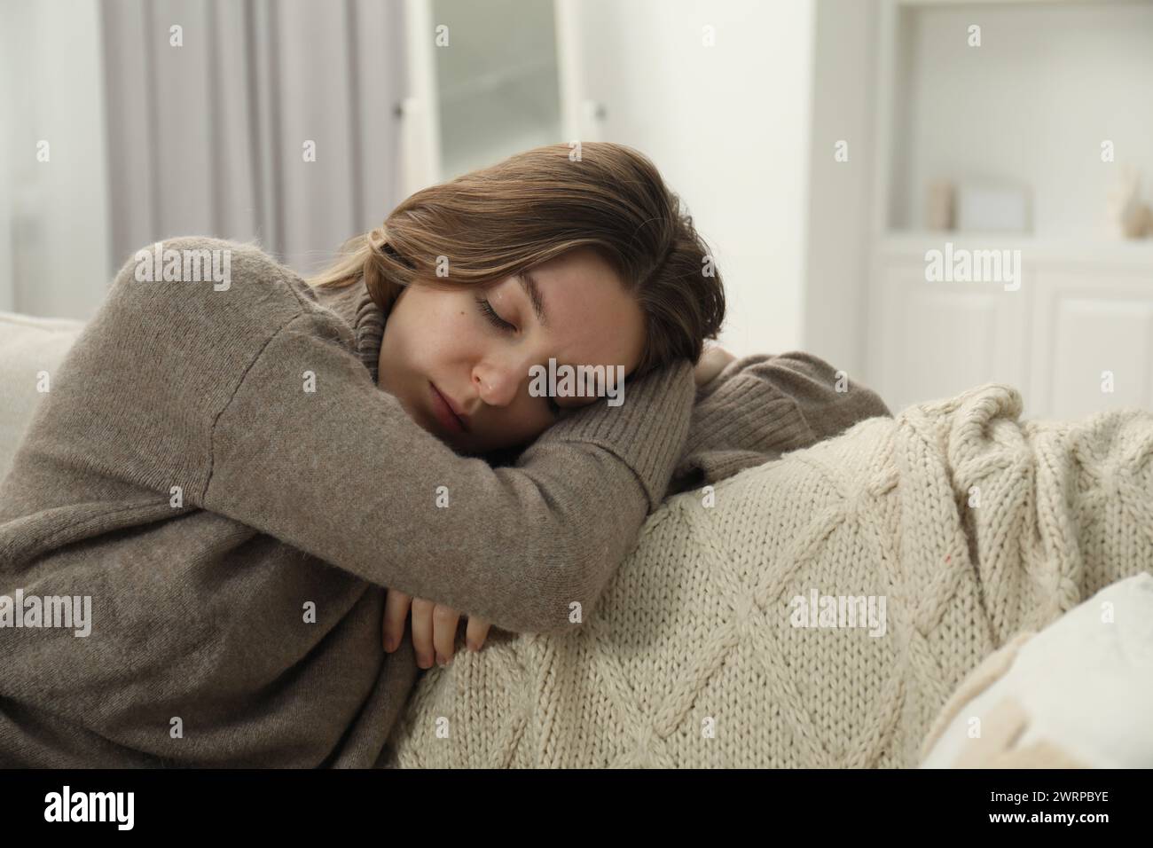 Sad young woman lying on sofa at home Stock Photo - Alamy