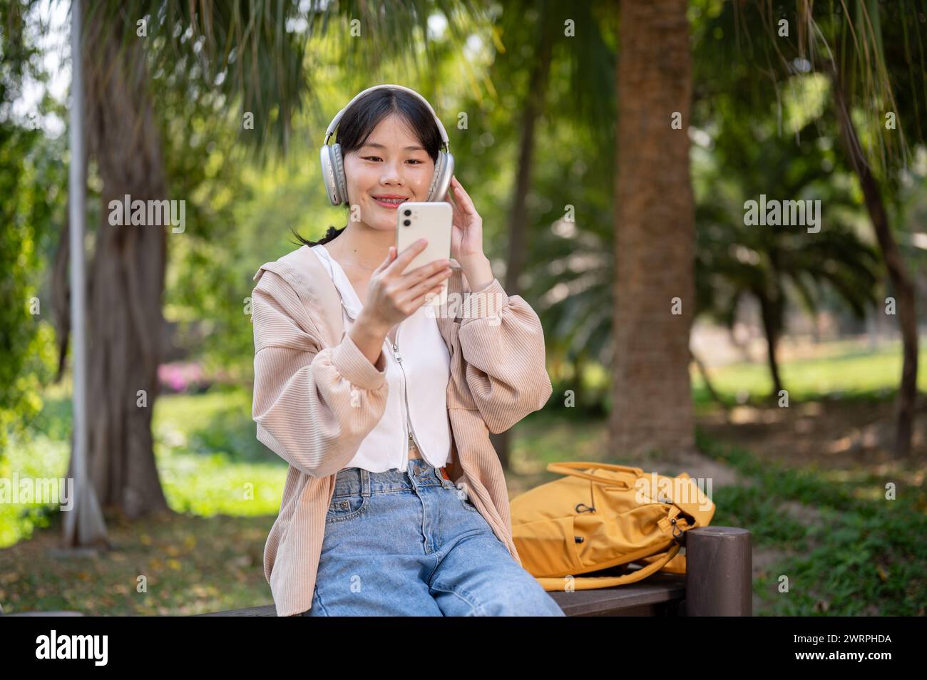 A pretty, happy young Asian female university student is relaxing on a ...