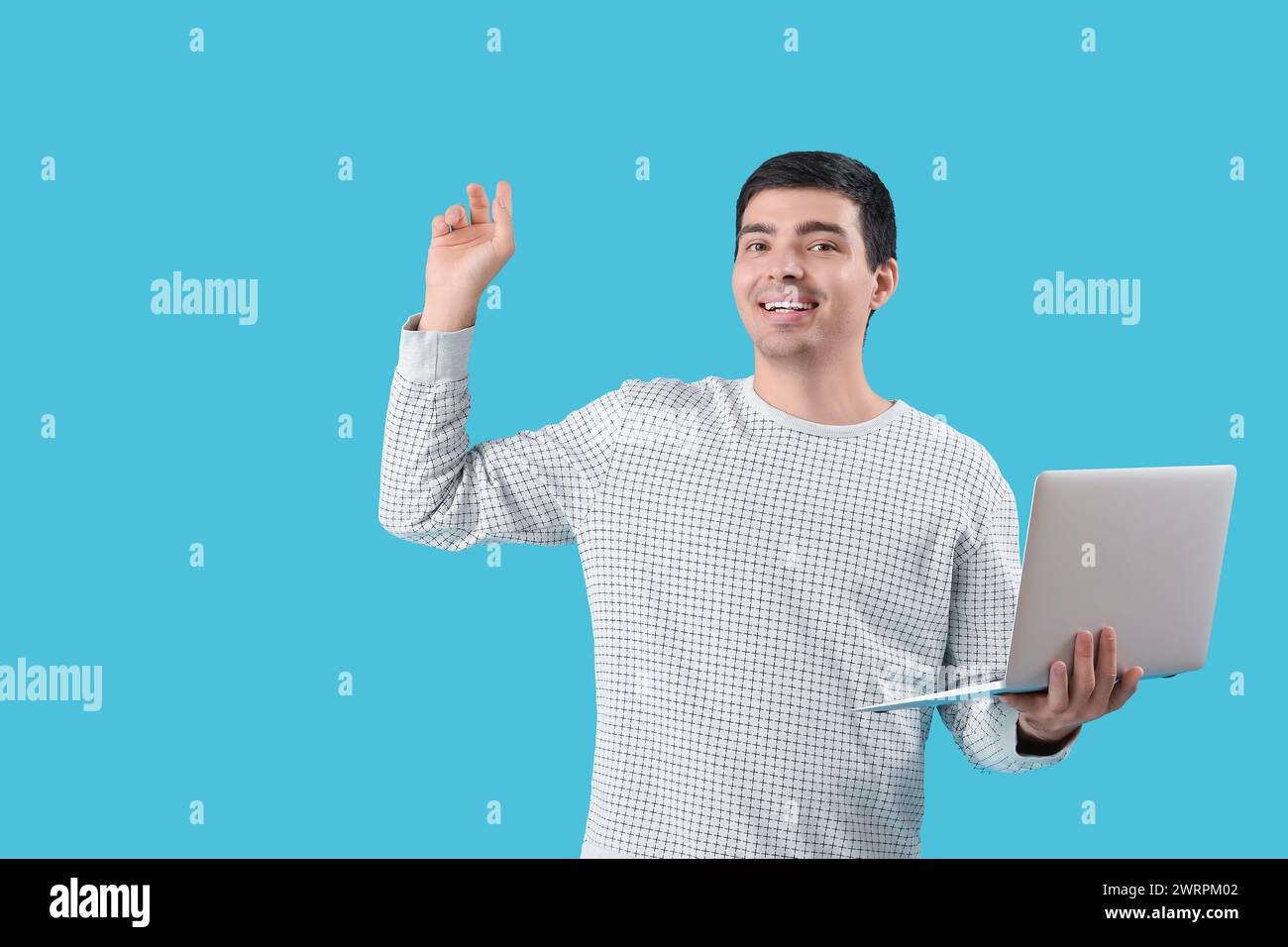 Male programmer with laptop pointing at something on blue background Stock Photo