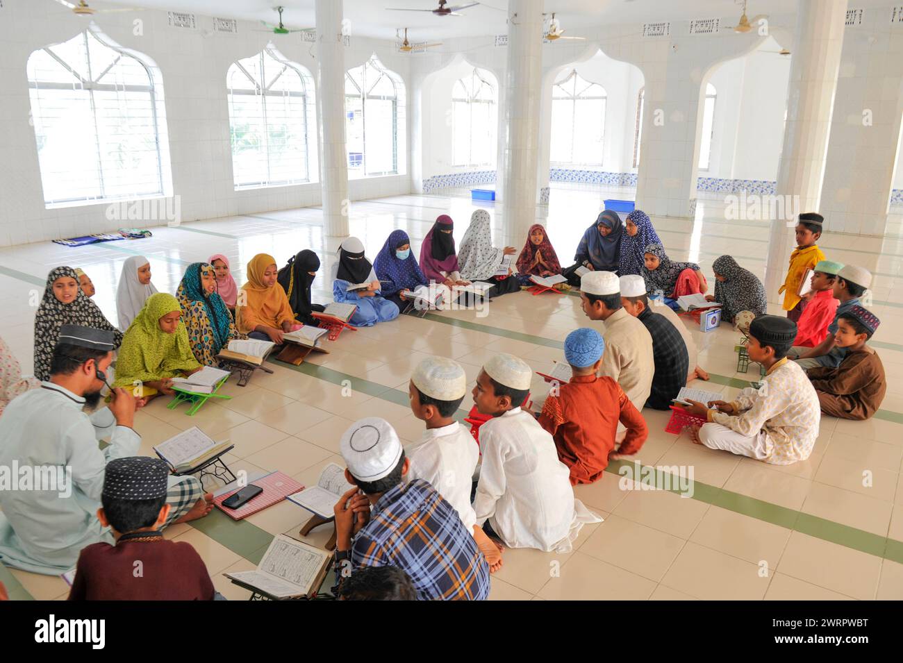 Non Exclusive: A Muslim reciting Quran during fasting on the 2nd day of Ramadan at the Al Jannah Mosque, Shamimabad Sylhet. Stock Photo