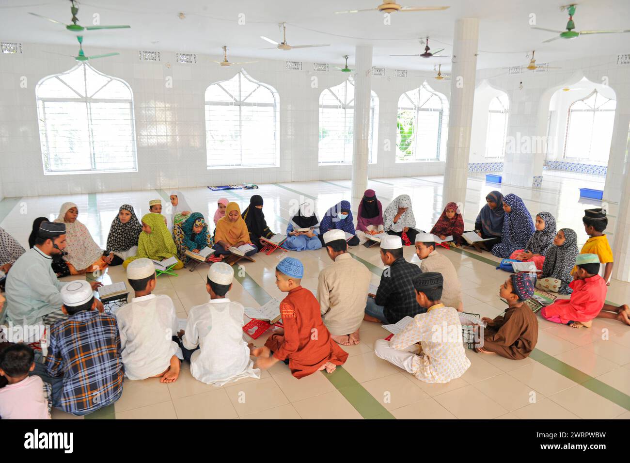 Non Exclusive: A Muslim reciting Quran during fasting on the 2nd day of Ramadan at the Al Jannah Mosque, Shamimabad Sylhet. Stock Photo