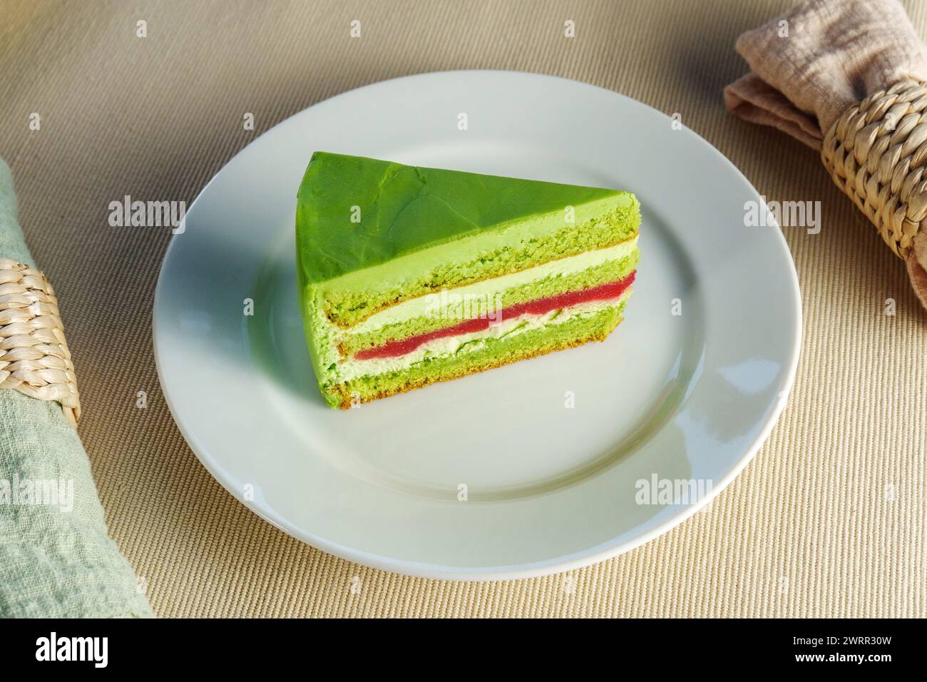 Showcasing a delectable piece of green cake on a pristine white plate, tempting the viewer Stock Photo