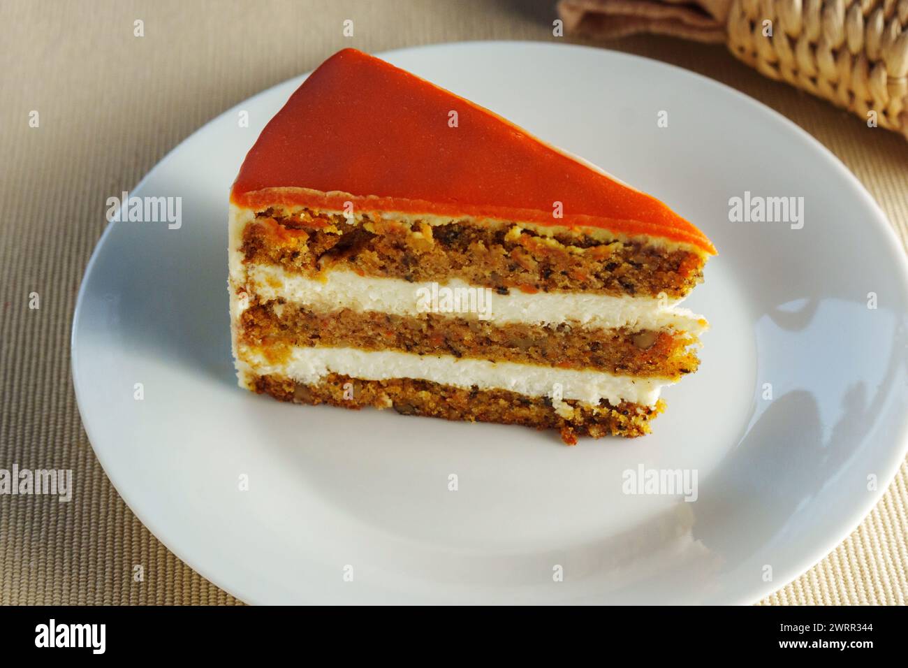 Featuring a slice of moist and flavorful carrot cake beautifully presented on a pristine white plate. Stock Photo