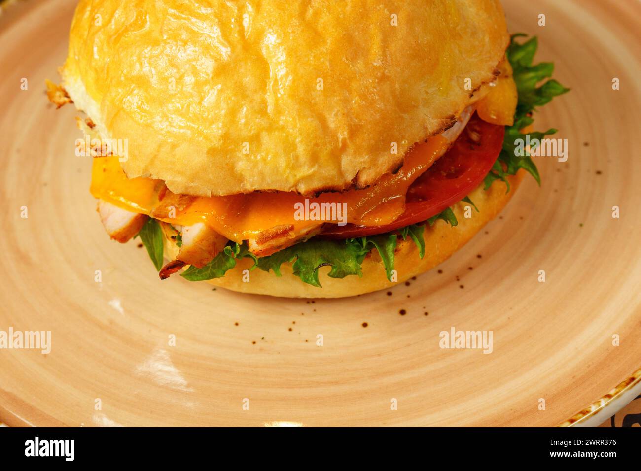 Cheeseburger topped with lettuce and various toppings placed on a plate, ready to be enjoyed. Stock Photo