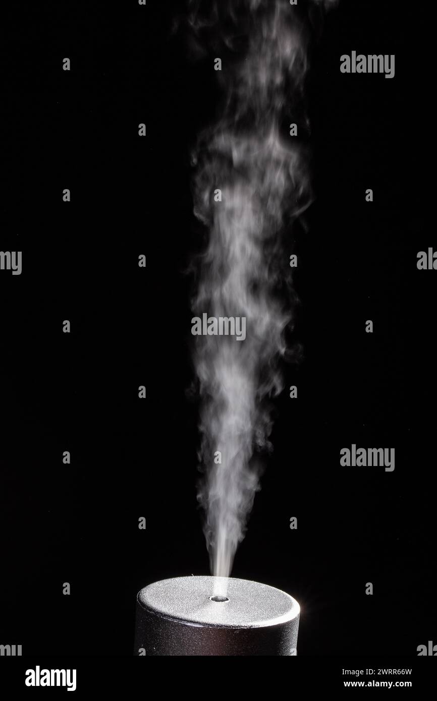 Captivating image of a steady stream of smoke emanating from a cylindrical object, isolated against a dark background, resembling scientific or indust Stock Photo