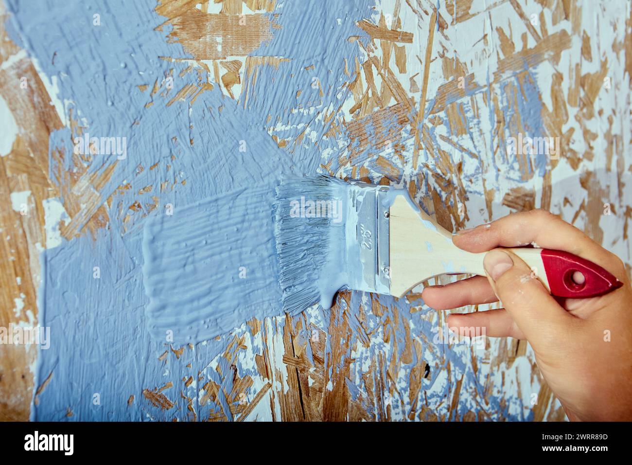 Interior painting, house painter applies brush strokes with gray paint