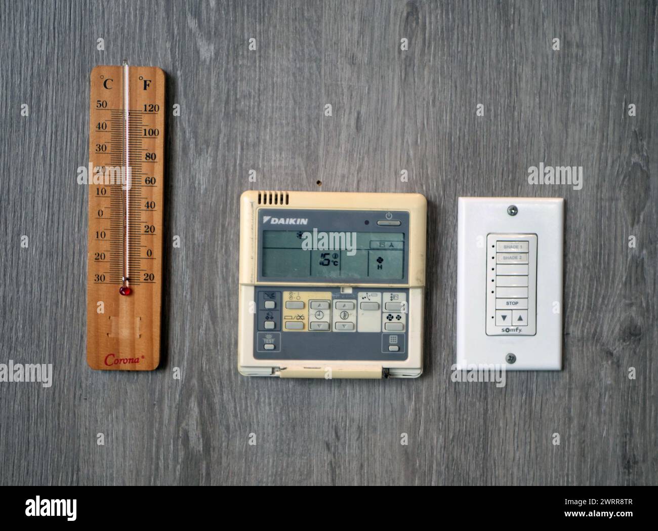 thermometer, AC remote and light switch attached to the wall Stock Photo