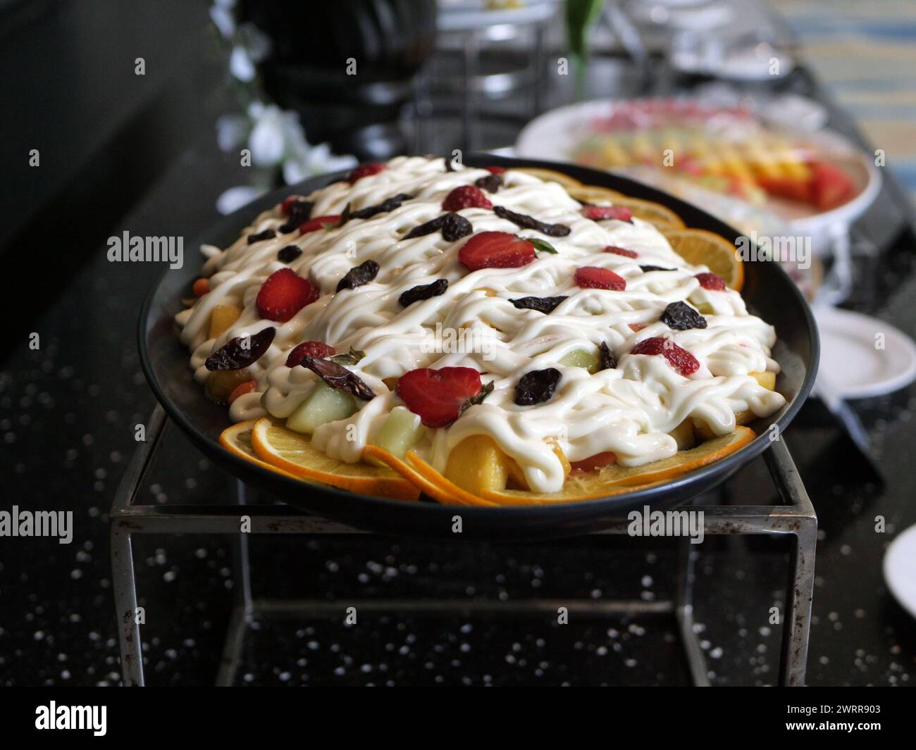 fruit salad in a black ceramic container on the table Stock Photo