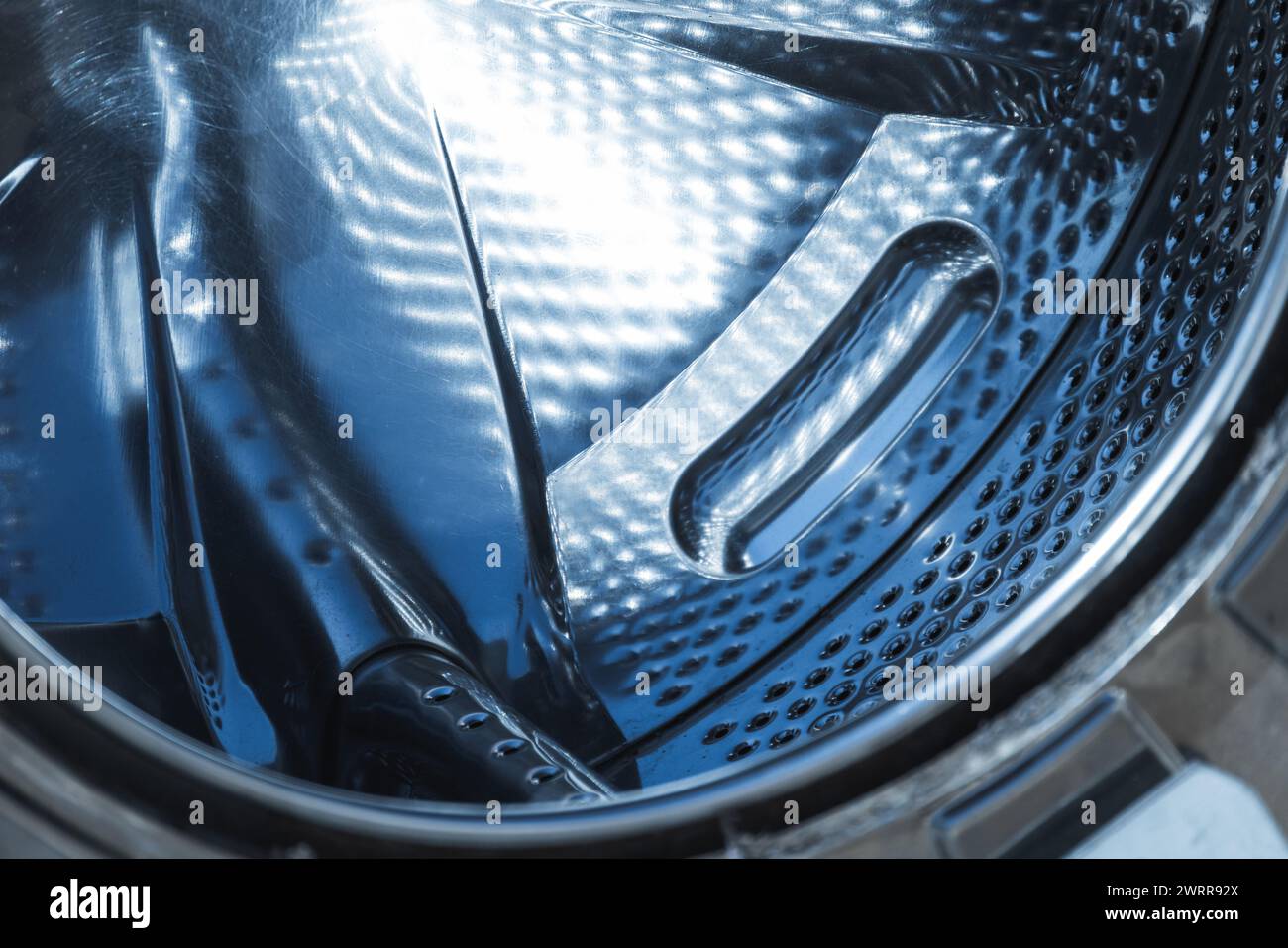 Inner space of an empty washing machine drum made of stainless steel, abstract industrial background texture Stock Photo