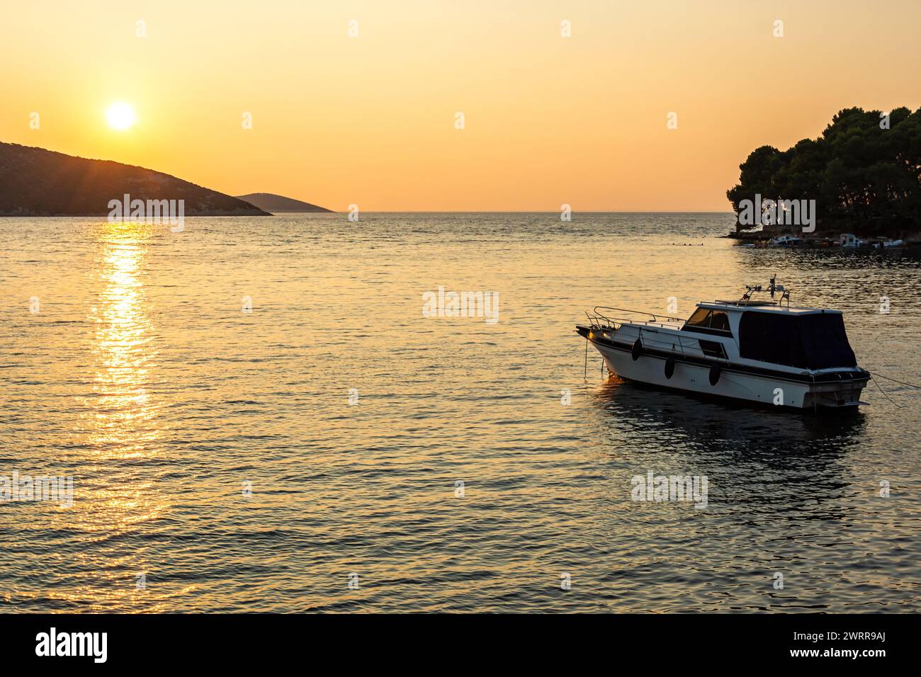 Boat anchoring in a beautiful bay (Osor) at sunset on the island of Cres-Losinj in the Adriatic Sea, Croatia Stock Photo