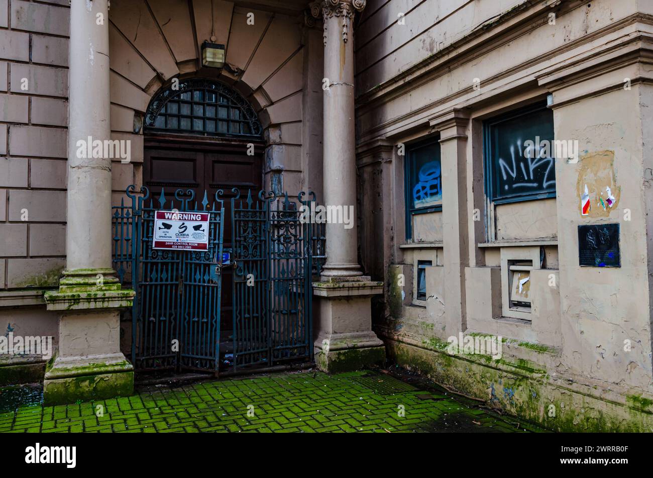 Belfast County Antrim Northern Ireland February 23 2024 -Derelict building in the centre of Belfast with a padlocked double gates with Georgian pillar Stock Photo