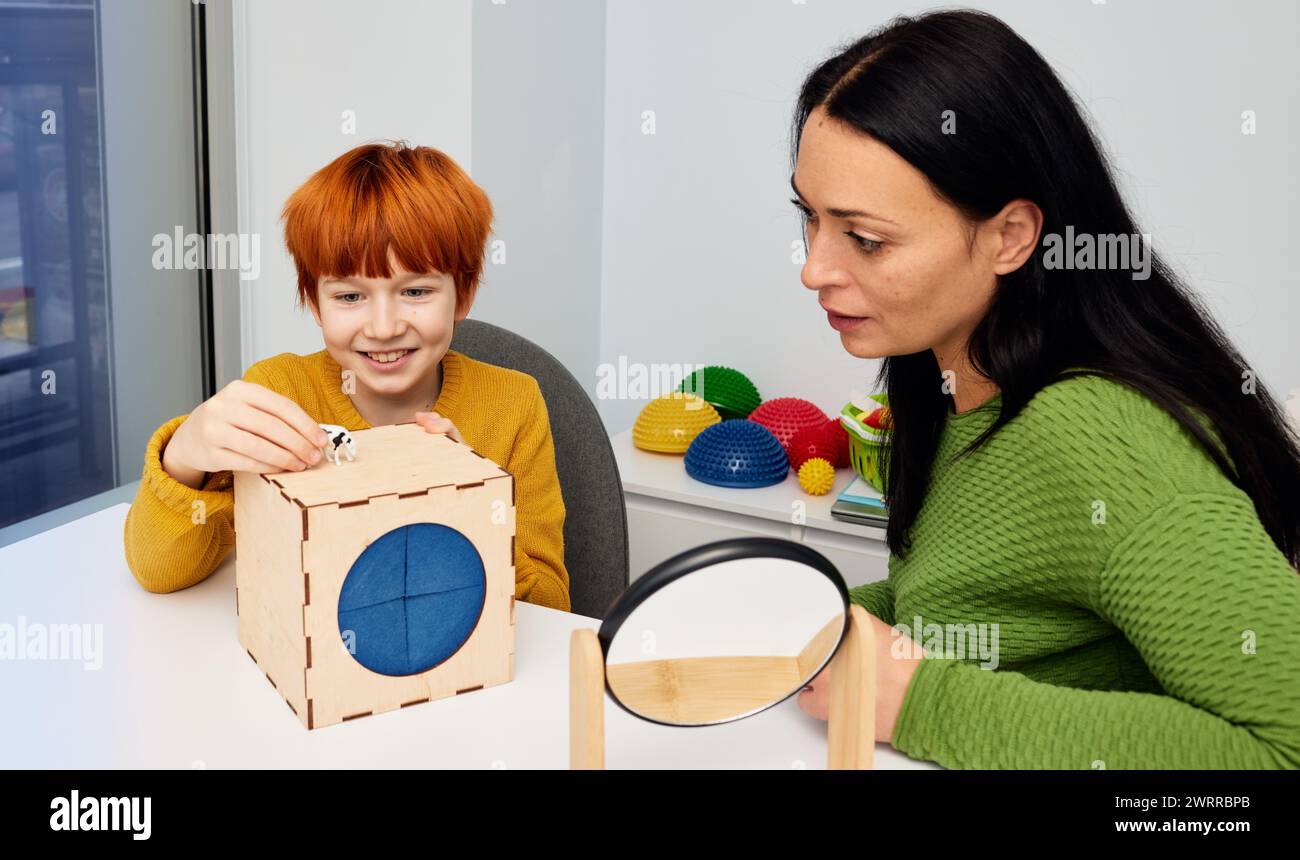 Speech therapy games. Male child patient training his pronunciation with private child development specialist while session in game form with toys Stock Photo