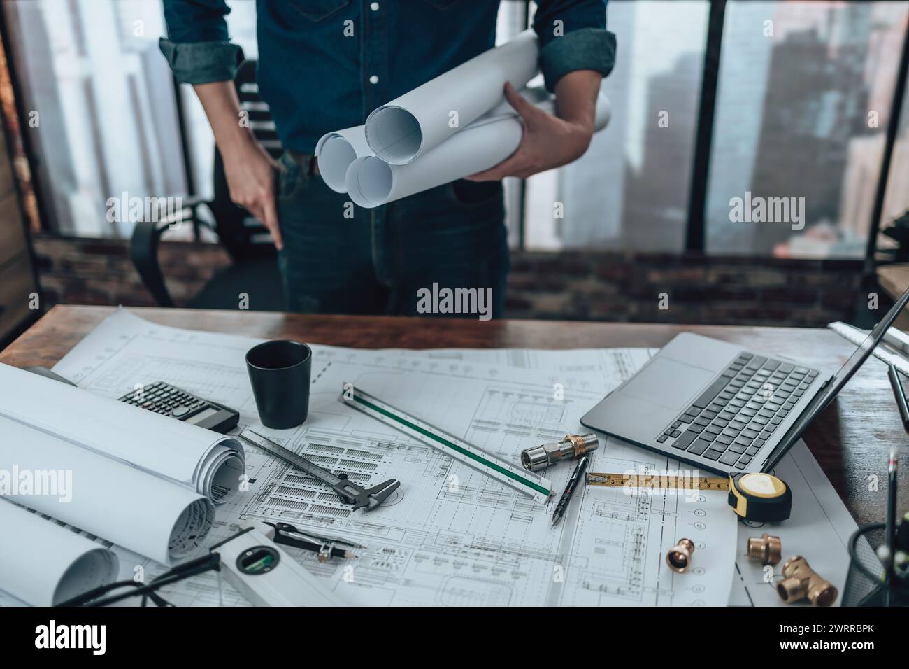 Engineering holding paper roll drawings in the office and Calculator ...