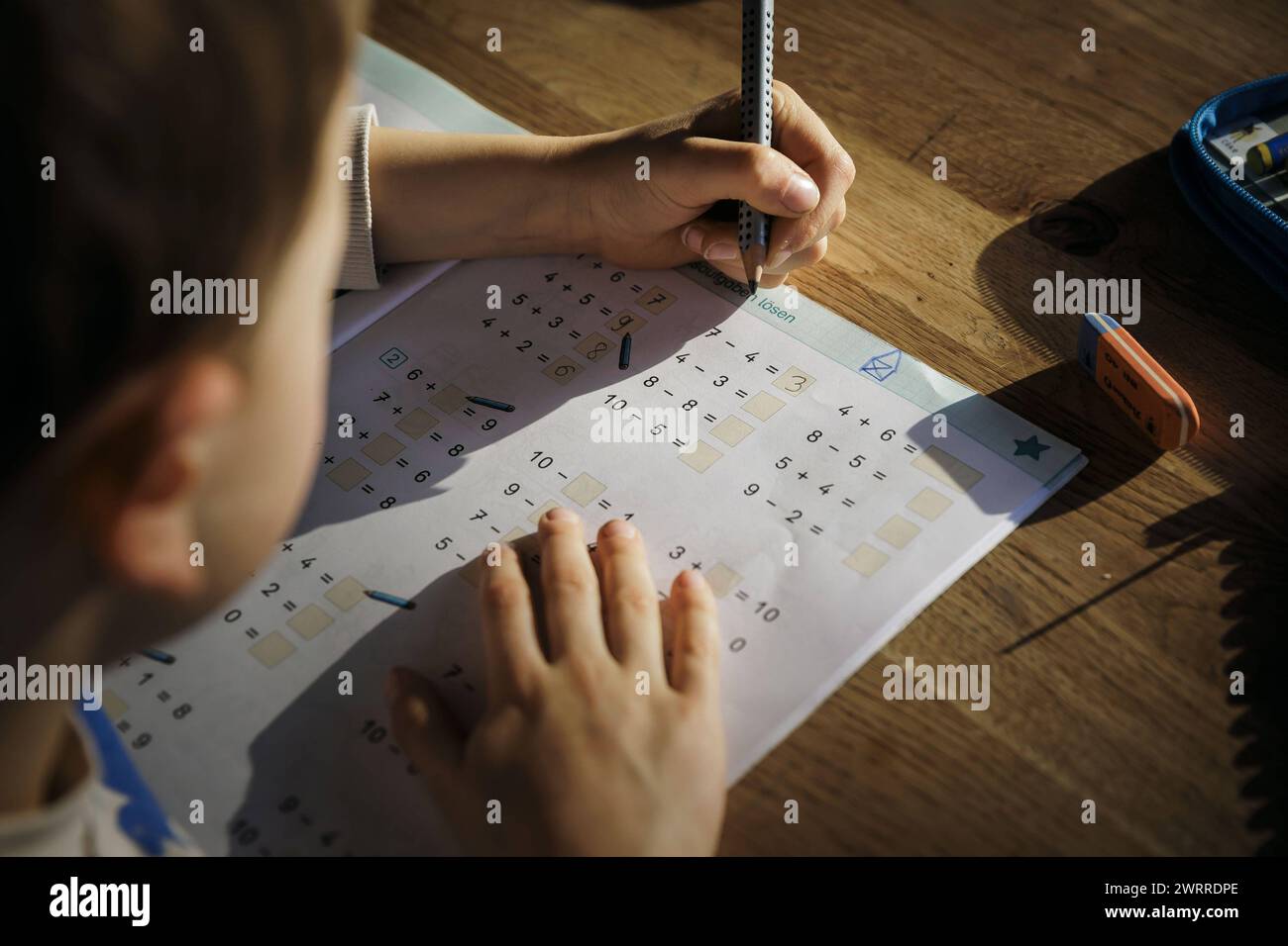 Ein sechsjaehriger Junge macht zu Hause Mathematik-Hausaufgaben der ersten Klasse in einem Arbeitsheft. Berlin, 13.03.2024. Berlin Deutschland *** A s Stock Photo
