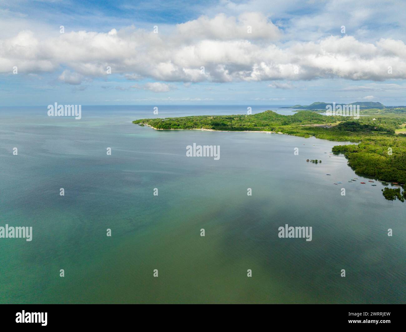 Drone view of tropical island with green plants surrounded by turquoise