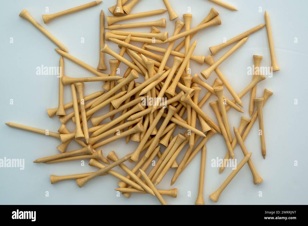 A small pile of natural wood colour bamboo golf tees on a white surface Stock Photo