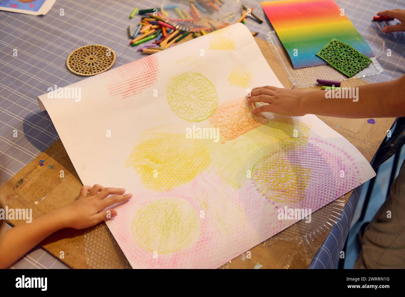 Close-up hands of children drawing with pastel color pencils on ...